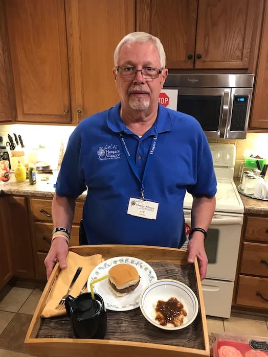 Al Poeppel holding a tray with a hamburger, mashed potatoes with gravy and a beverage