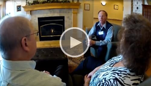Hospice professional sitting down speaking with a man and woman couple