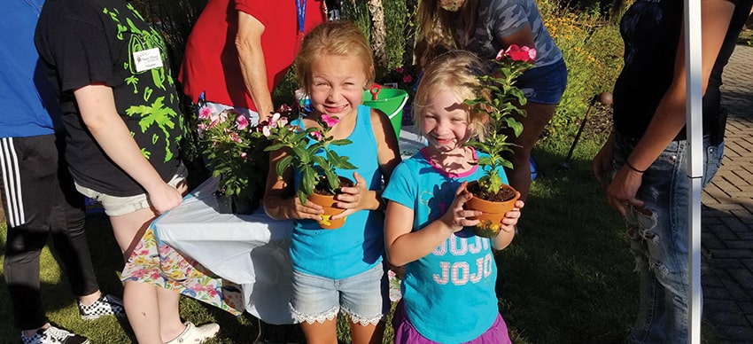 Two young girls holding potted plants
