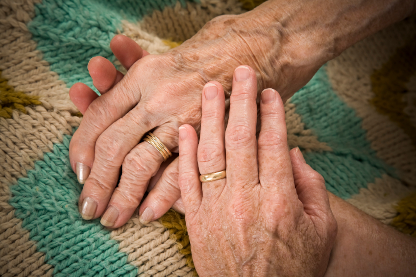 baby boomer daughter holds her senior mother's hand