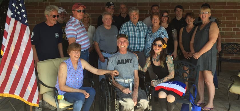 A group of people standing next to a war veteran sitting in a wheel chair